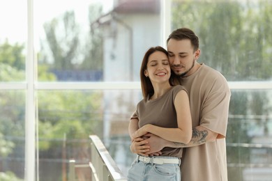 Photo of Happy couple hugging at home. Space for text