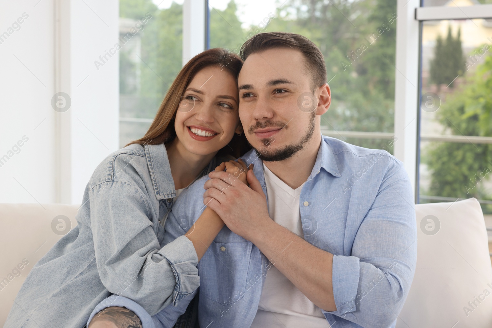 Photo of Happy couple holding hands on sofa at home