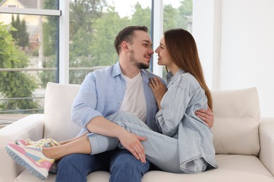 Man hugging his happy girlfriend on sofa at home