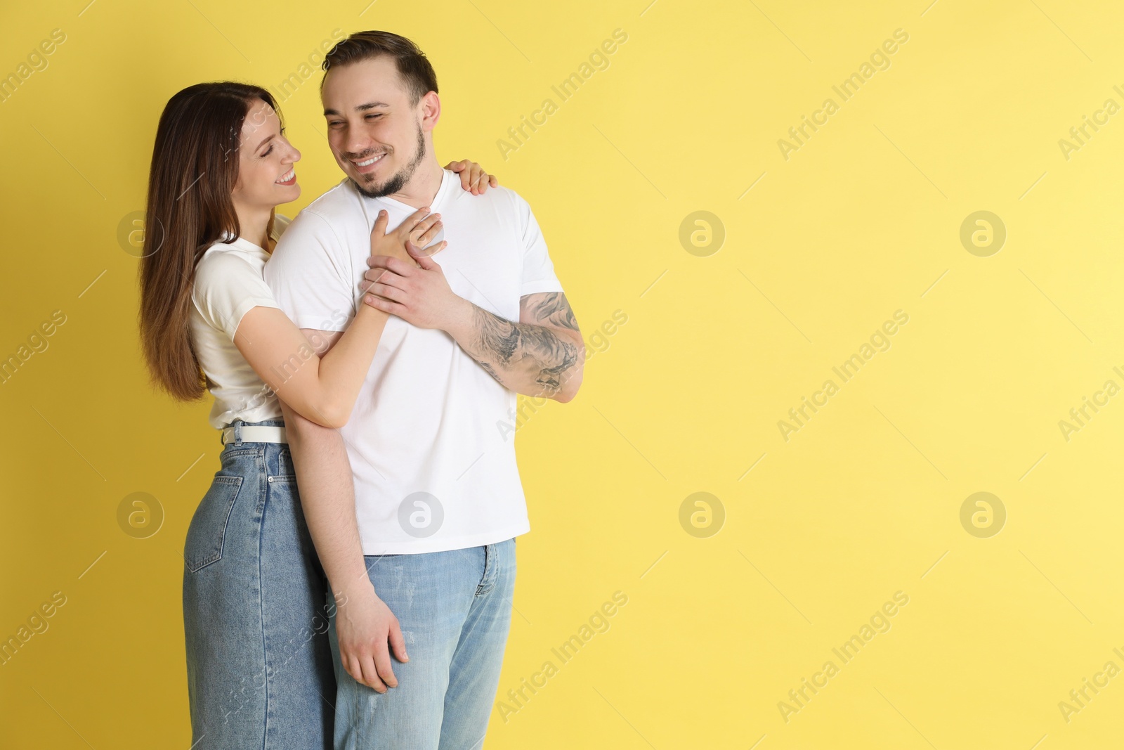 Photo of Happy couple hugging on yellow background. Space for text