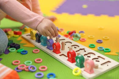 Photo of Little girl playing with game Fishing for Numbers on puzzle mat, closeup. Kindergarten activities for learning mathematics