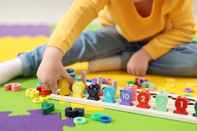 Photo of Little boy playing with game Fishing for Numbers on puzzle mat, closeup. Kindergarten activities for learning mathematics