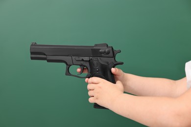 Child with gun against chalkboard, closeup. School shooting