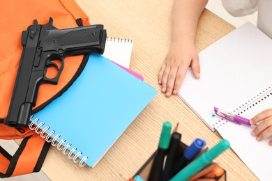 Photo of Child at desk with school stationery and gun, closeup