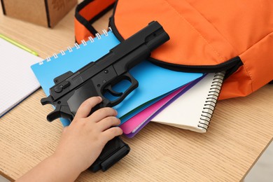 Photo of Child with gun and school stationery at desk, closeup