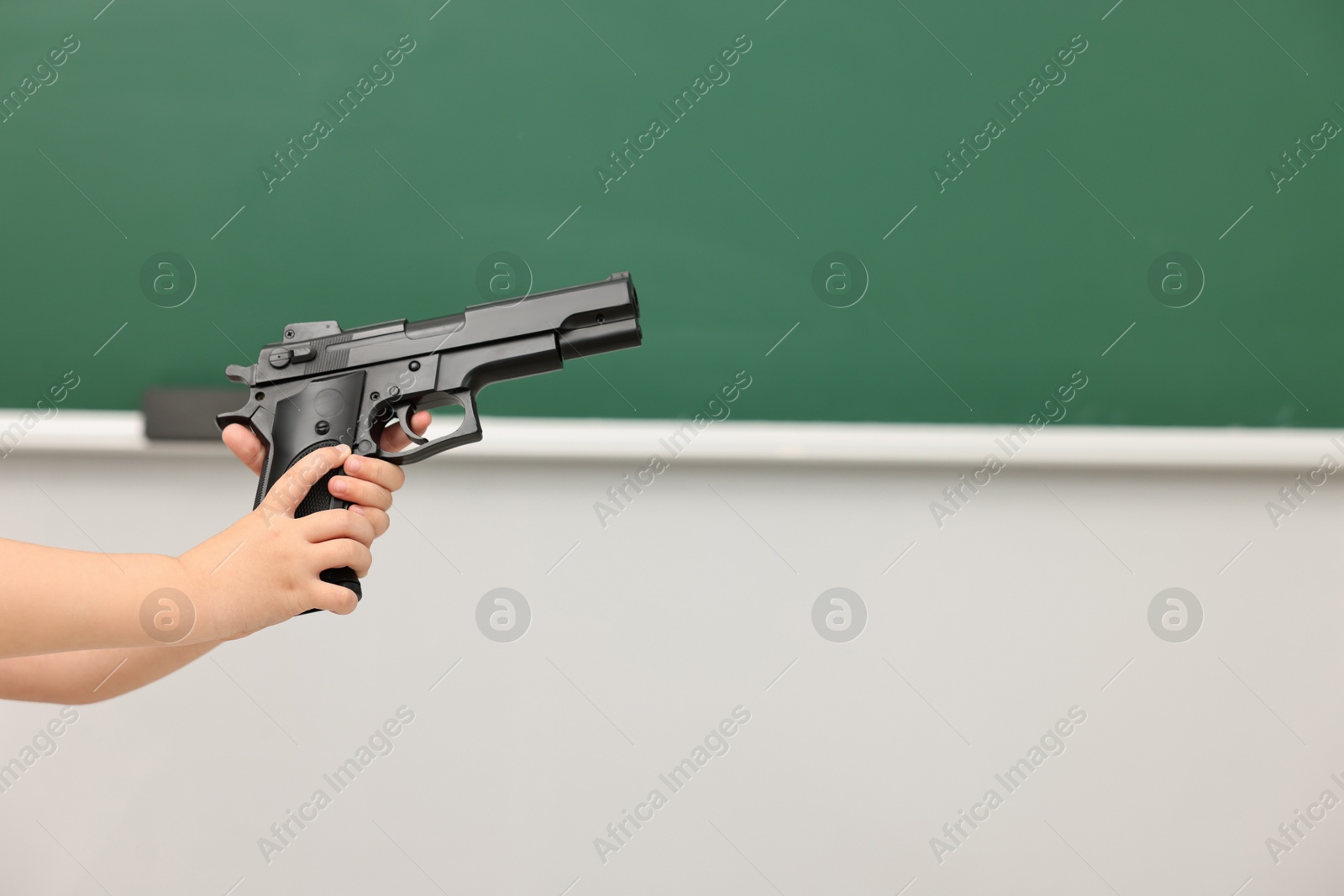 Photo of Child with gun in classroom, closeup. School shooting