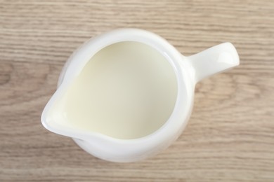 Jug of fresh milk isolated on wooden table, top view