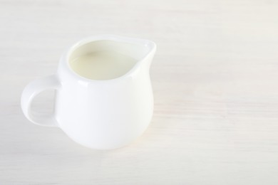 Jug of fresh milk isolated on wooden table, space for text