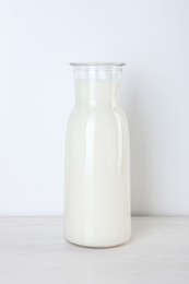 Photo of Glass carafe of fresh milk on wooden table