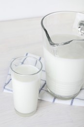 Jug and glass of fresh milk on wooden table