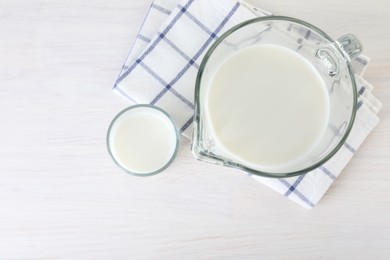 Jug and glass of fresh milk on wooden table, top view