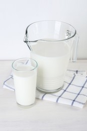 Jug and glass of fresh milk on wooden table