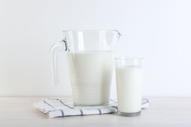 Jug and glass of fresh milk on wooden table
