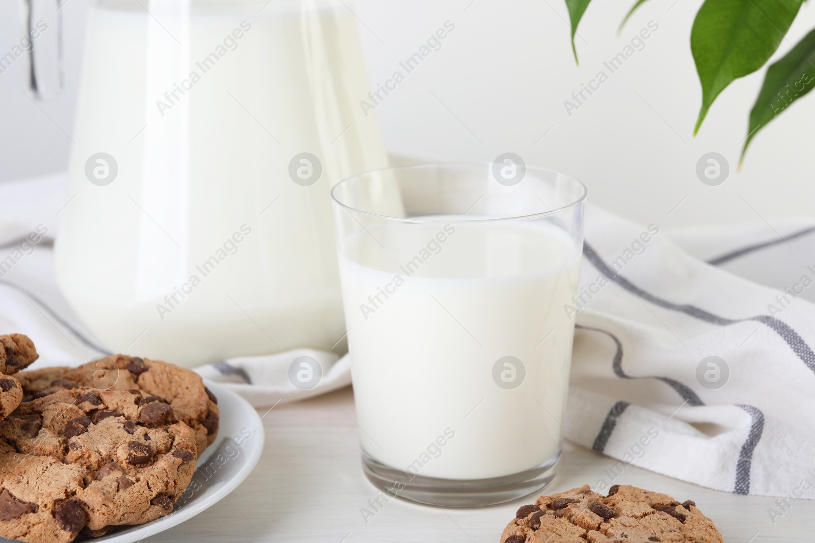 Photo of Jug of fresh milk, glass and cookies on wooden table