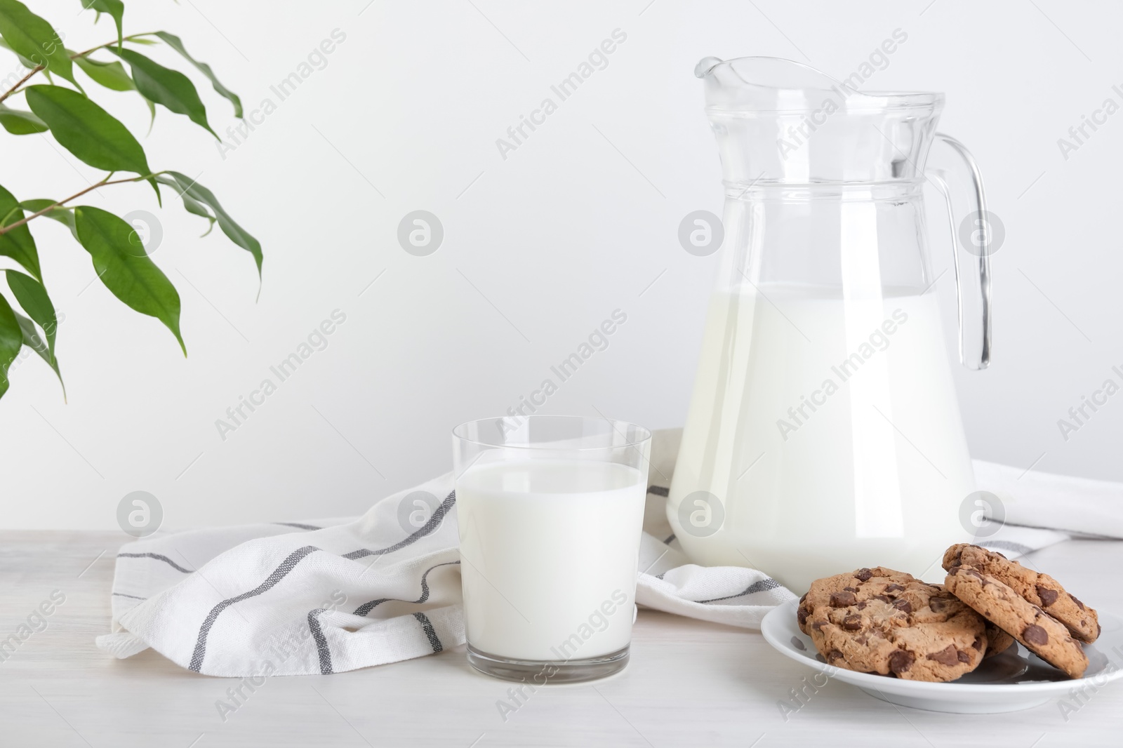 Photo of Jug of fresh milk, glass and cookies on wooden table