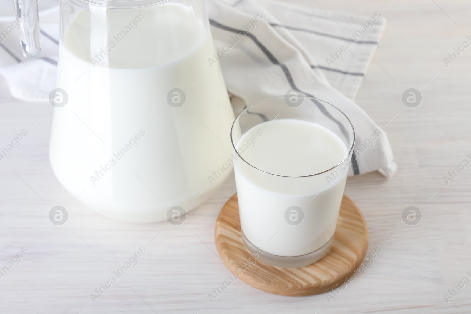 Photo of Jug and glass of fresh milk on wooden table