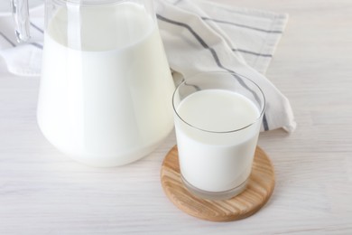 Jug and glass of fresh milk on wooden table