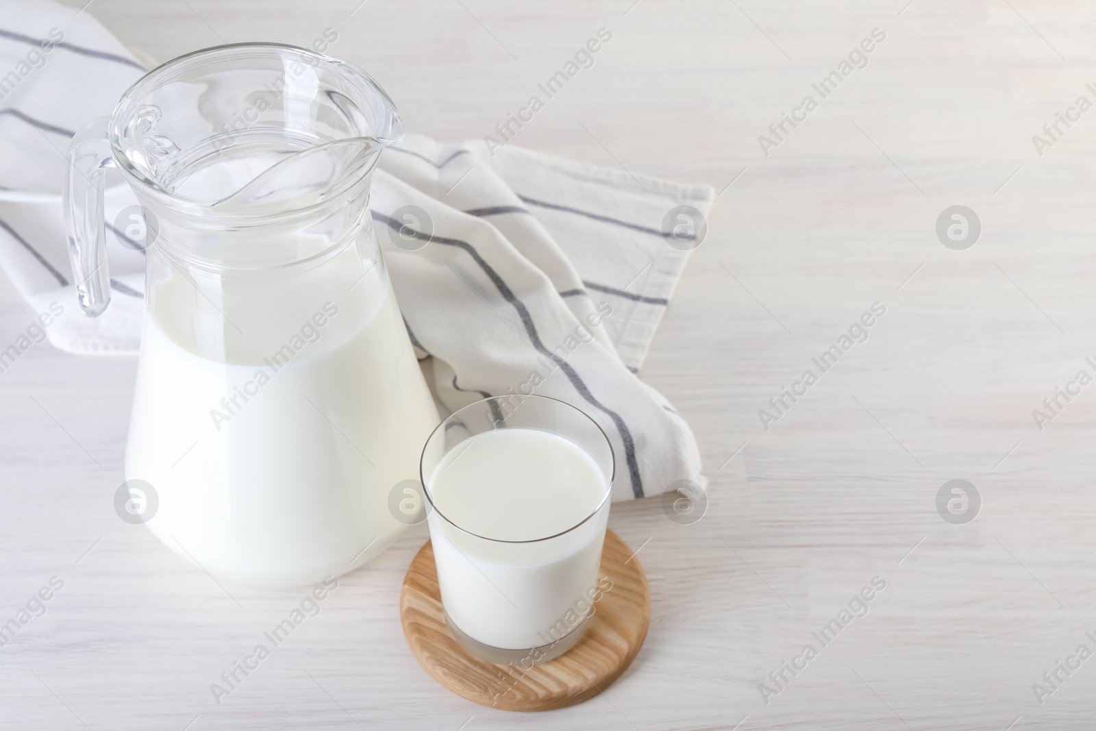 Photo of Jug and glass of fresh milk on wooden table