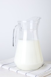 Glass jug of fresh milk on table