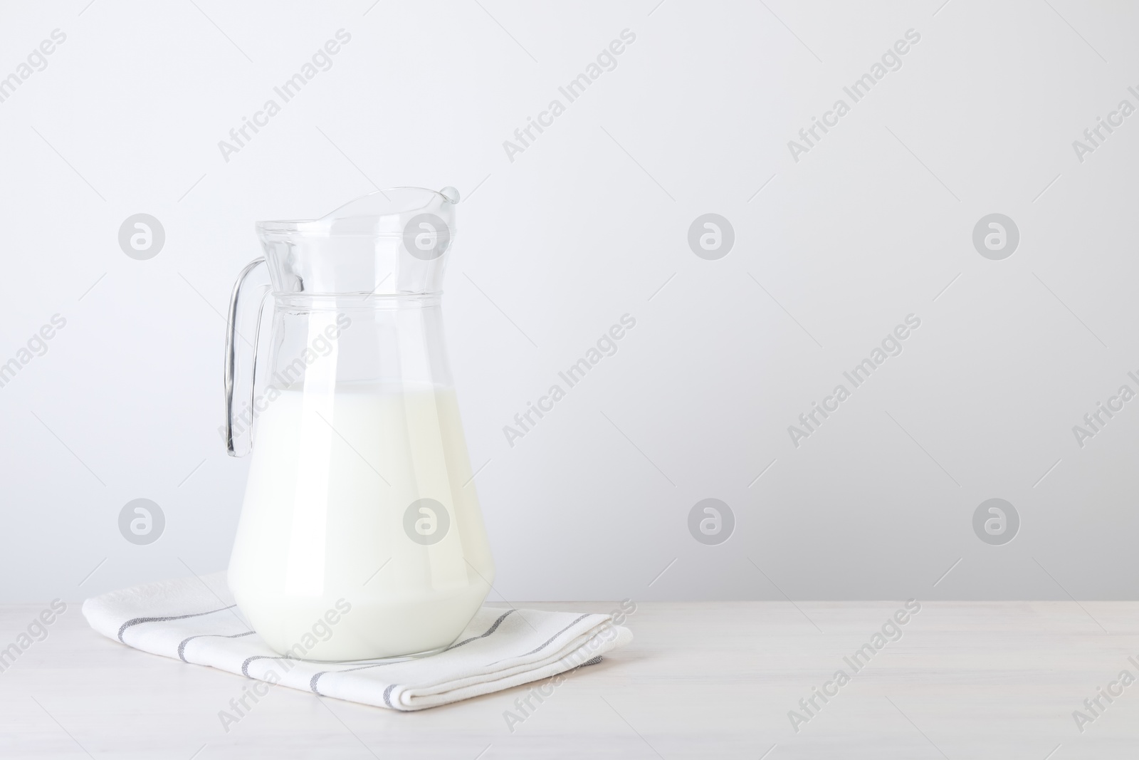 Photo of Jug of fresh milk on wooden table, space for text