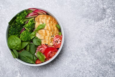 Healthy meal. Delicious chicken, vegetables and spinach in bowl on light grey table, top view. Space for text