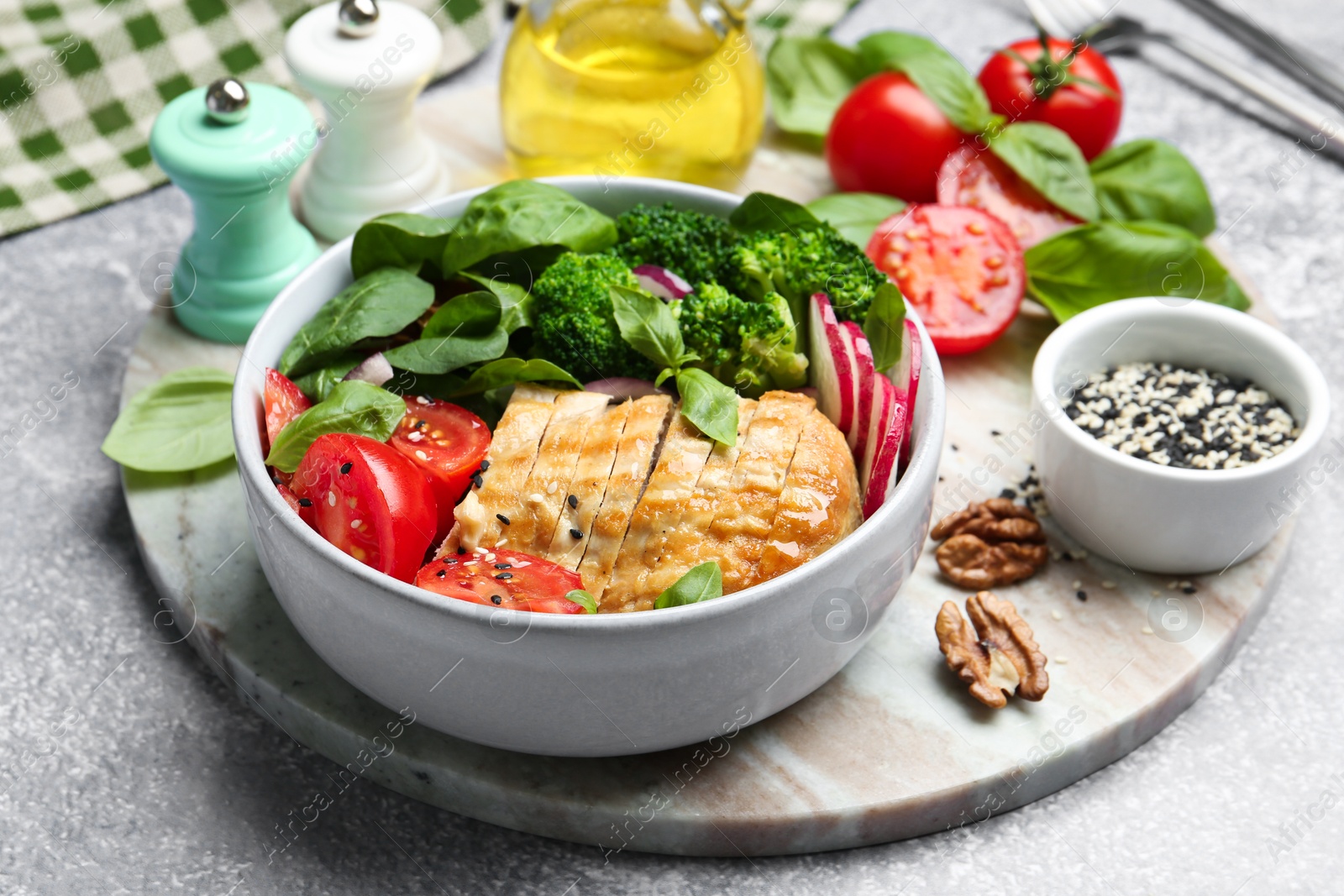 Photo of Healthy meal. Delicious chicken, vegetables and spinach served on light grey table