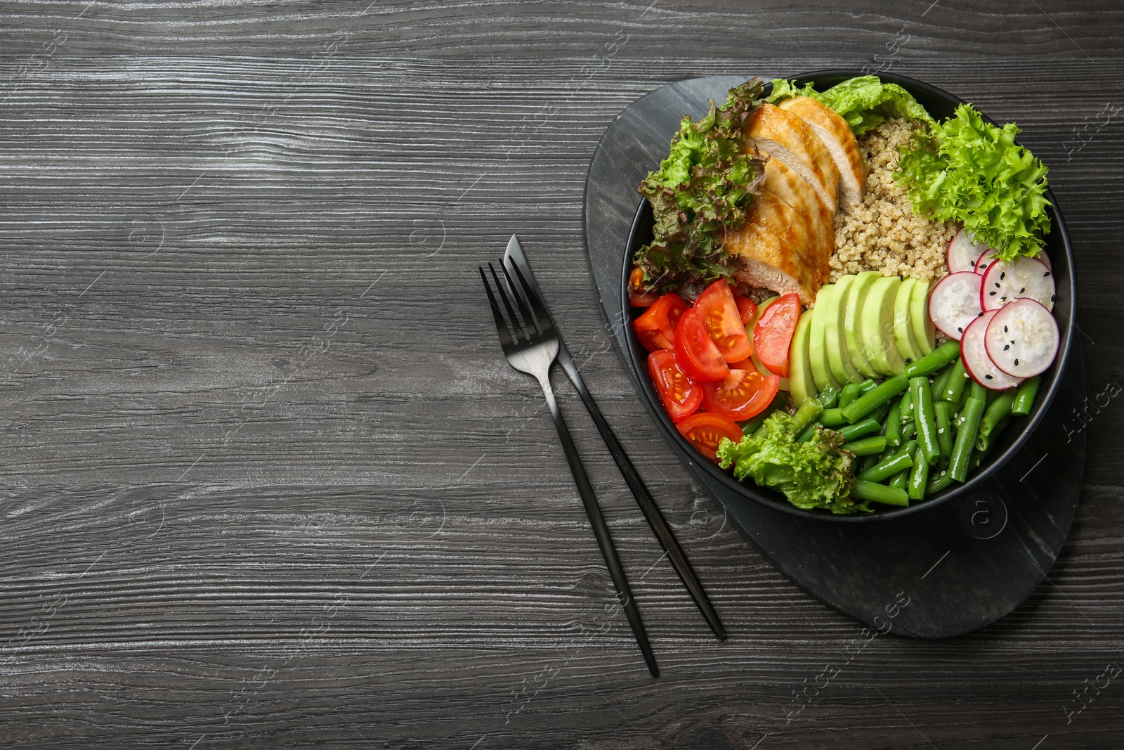 Photo of Healthy meal. Tasty products in bowl and cutlery on black wooden table, top view. Space for text