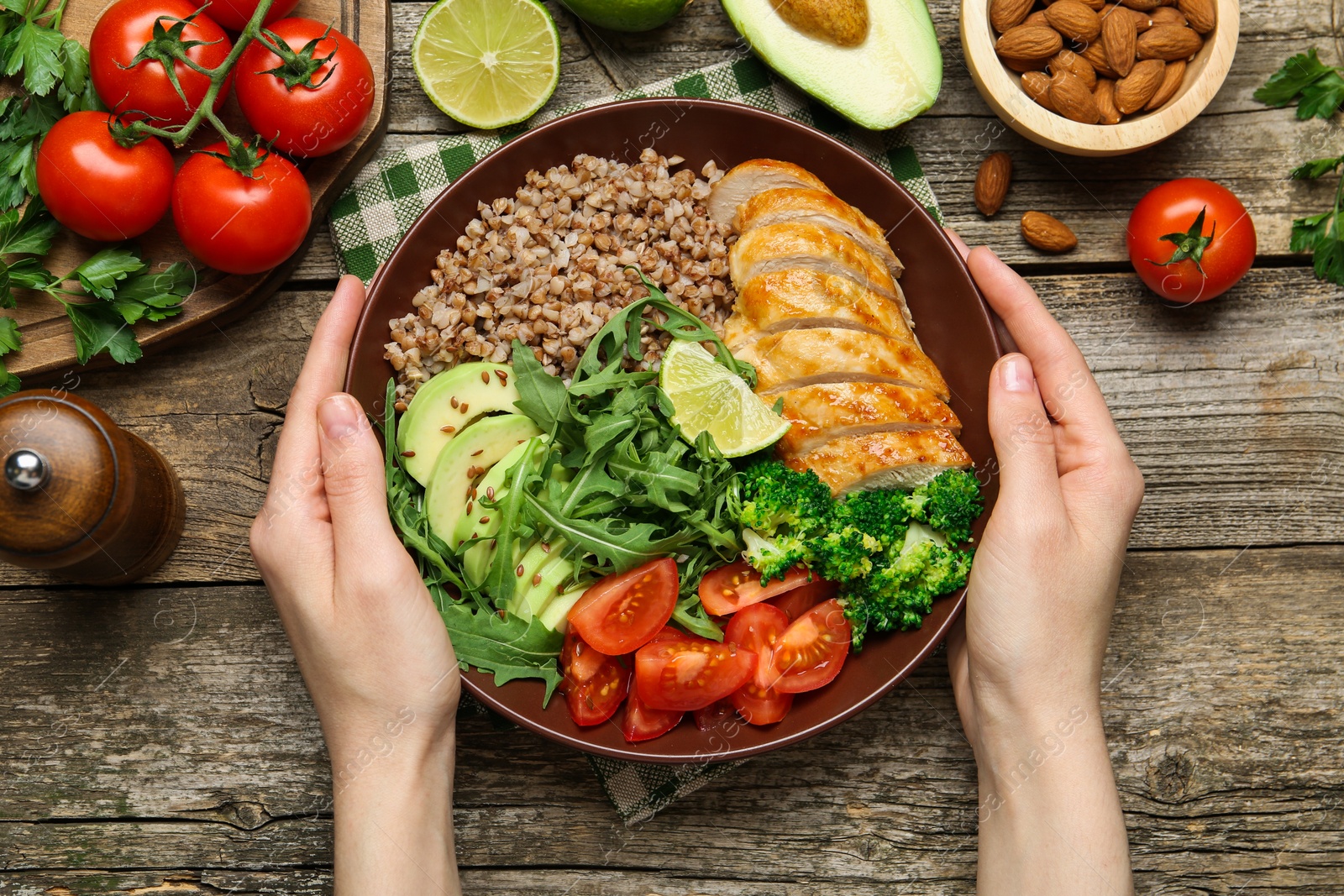 Photo of Healthy meal. Woman with tasty products in bowl at wooden table, top view