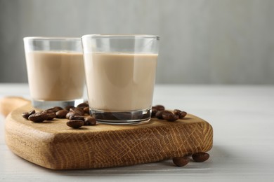 Coffee cream liqueur in glasses and beans on white wooden table