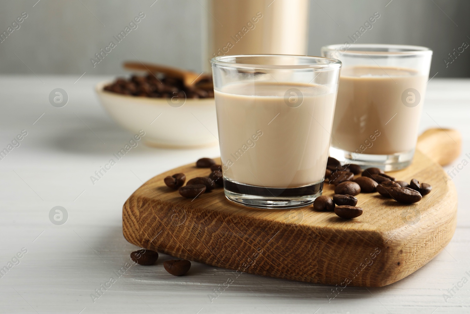 Photo of Coffee cream liqueur in glasses and beans on white wooden table