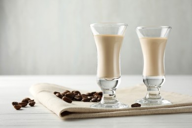 Coffee cream liqueur in glasses and beans on white wooden table