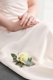 Photo of Bride with boutonniere for her groom on dress, closeup