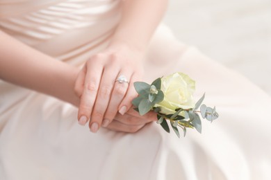 Photo of Bride holding boutonniere for her groom indoors, closeup