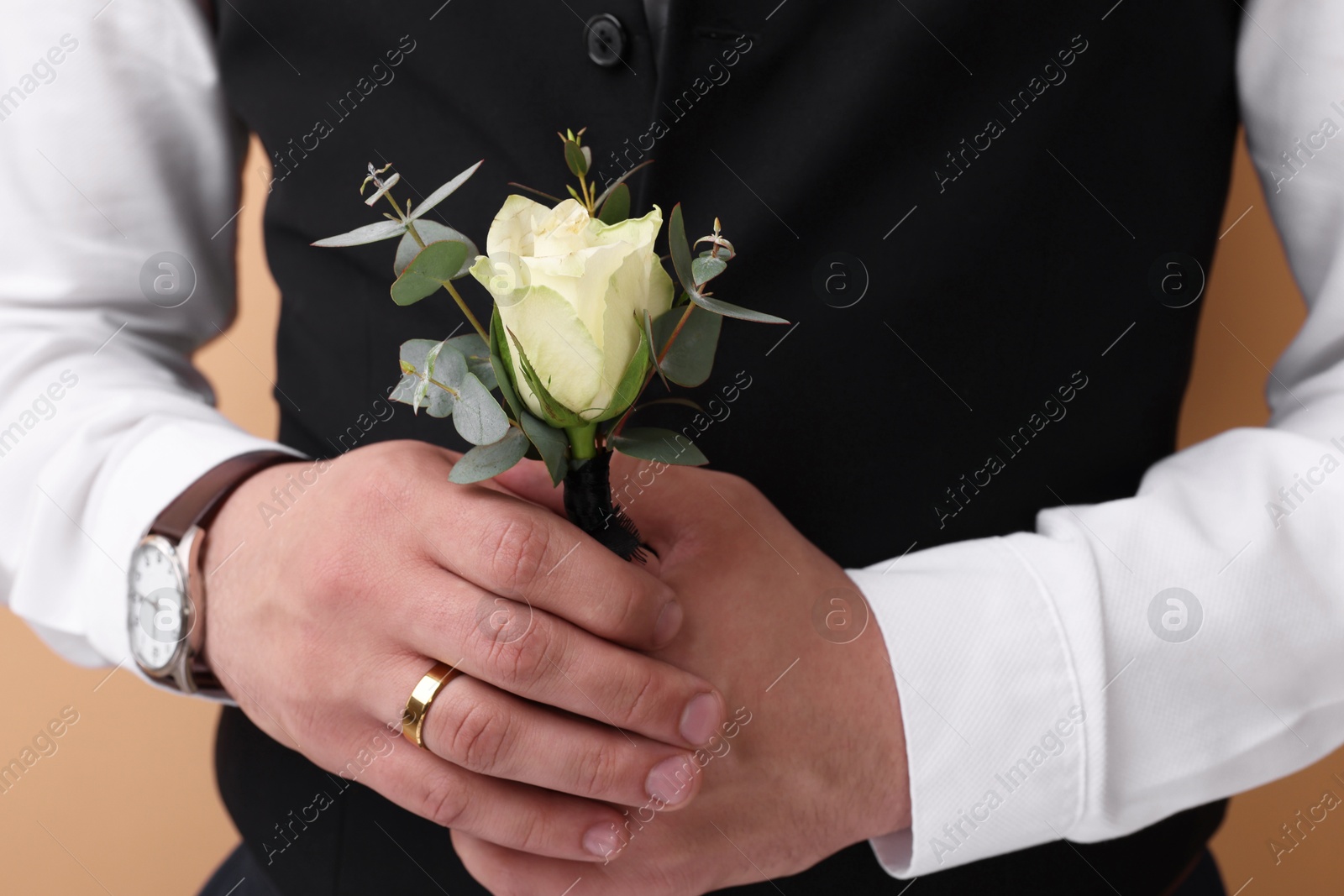Photo of Groom with boutonniere on beige background, closeup. Wedding accessory
