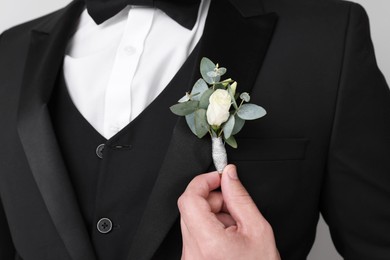 Photo of Groom with boutonniere on light grey background, closeup. Wedding accessory