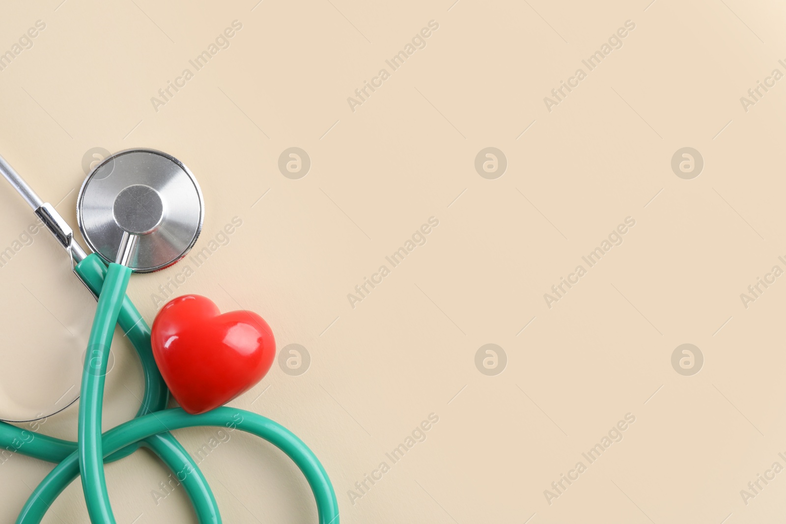 Photo of Stethoscope and red heart on beige background, top view. Space for text