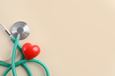 Photo of Stethoscope and red heart on beige background, top view. Space for text