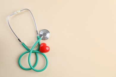 Stethoscope and red heart on beige background, top view. Space for text