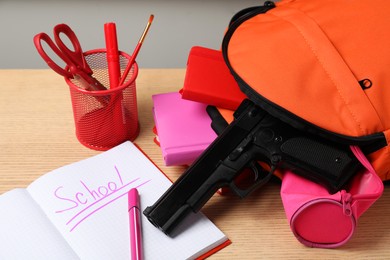 Gun and school stationery on wooden table