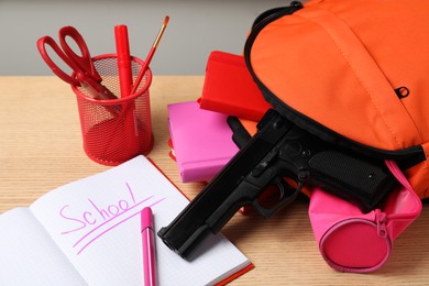 Photo of Gun and school stationery on wooden table