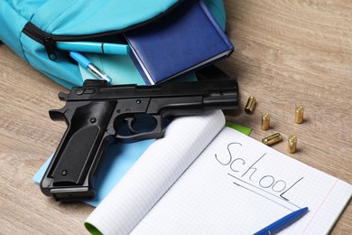 Photo of Gun, bullets and school stationery on wooden table