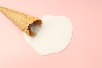 Photo of Melted ice cream and wafer cone on light pink background, top view. Space for text