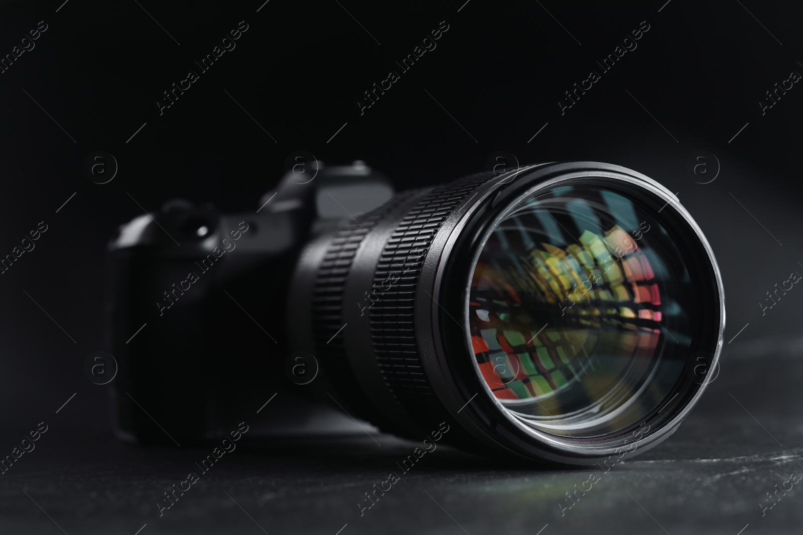 Photo of Modern photo camera on black table, closeup. Photographer's equipment