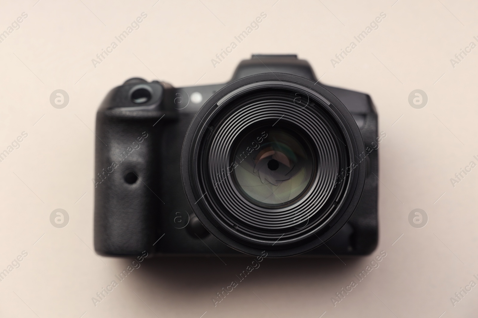 Photo of One modern photo camera on beige background, top view