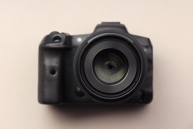 One modern photo camera on beige background, top view