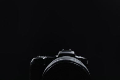 Photo of Modern photo camera on black background, closeup. Space for text