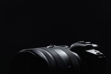 Modern photo camera on black background, closeup. Space for text