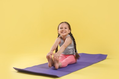 Photo of Cute little girl stretching on yellow background