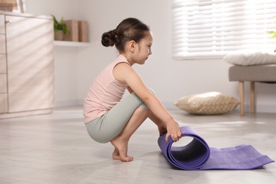 Cute little girl with fitness mat at home
