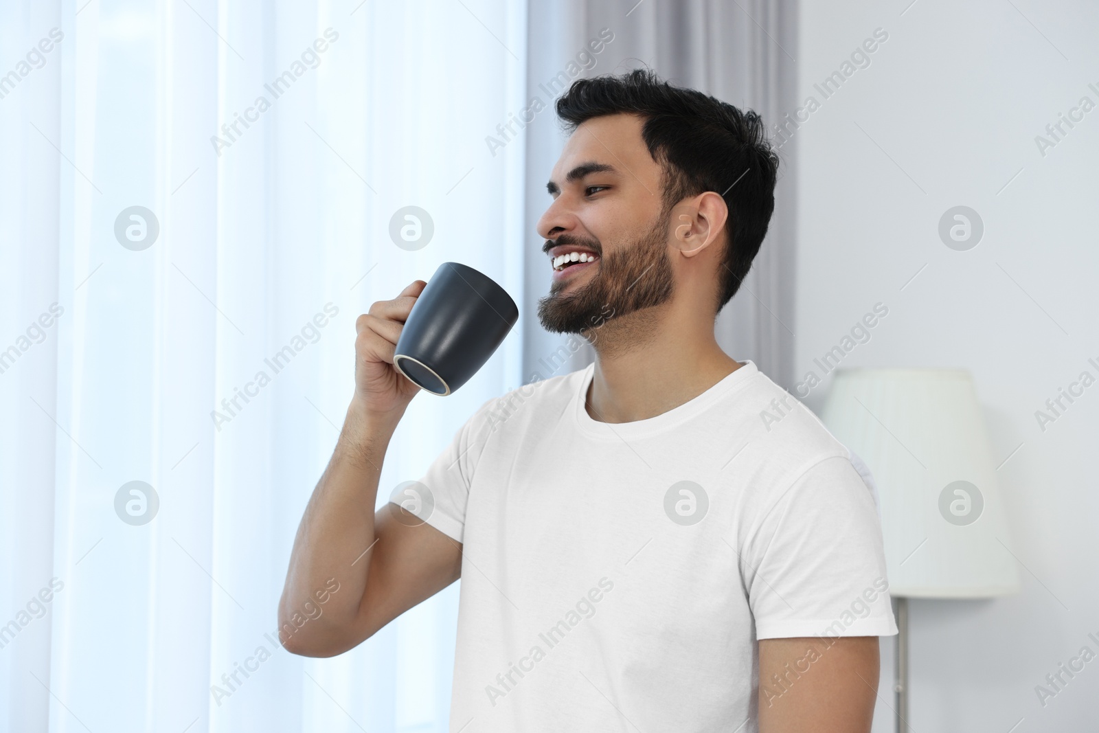 Photo of Happy man with cup of morning coffee at home